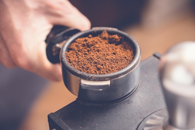 Barista met portafilter met verse koffie in de hand en bereidt perskoffie met sabotage Close-up