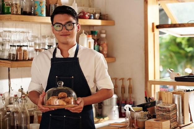 Barista met versgebakken croissants