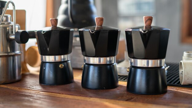 Photo barista pouring coffee from mocha pot coffee maker to a coffee cup hand holding italian classic mocha pot pouring coffee