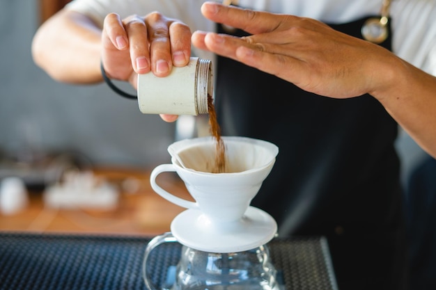 Photo barista pouring coffee from mocha pot coffee maker to a coffee cup hand holding italian classic mocha pot pouring coffee