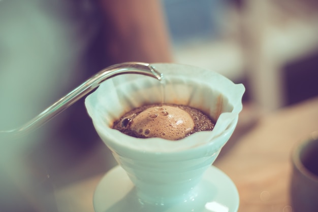 barista pouring hot water on coffee ground, home brewing process