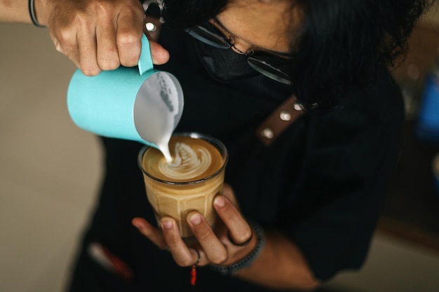 Il barista versa la schiuma di latte sul caffè, l'espresso e crea una perfetta latte art