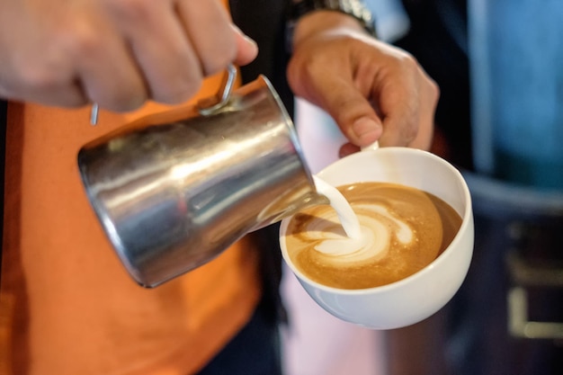 Barista pouring milk on coffee cup making heart