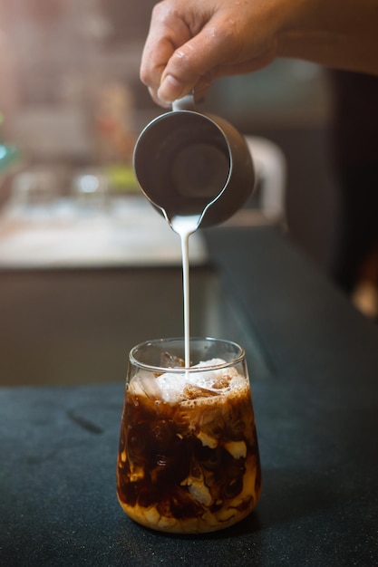 Barista pouring milk in glass