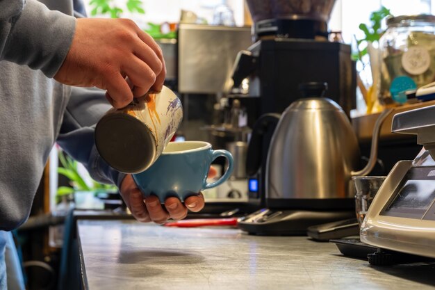 A barista pouring milk into the coffee cup making latte art