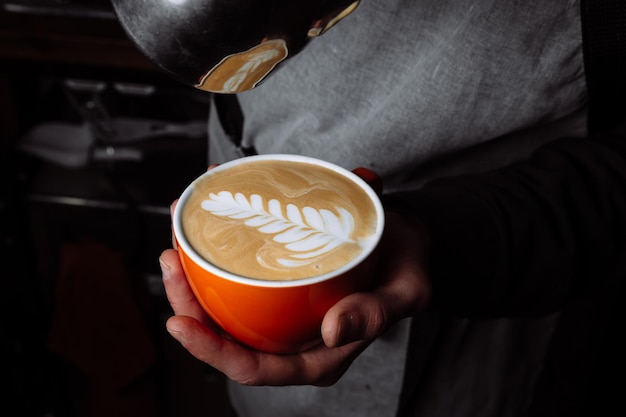 Barista pours warm milk into coffee