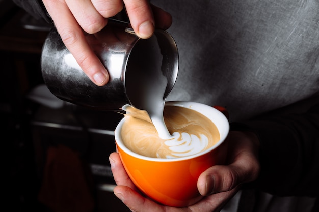 Barista pours warm milk into coffee