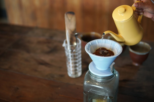 Photo barista preparing brewing coffee with coffee maker and drip kettle. dripping ground coffee with filter