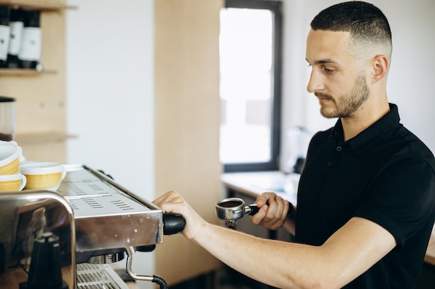 Barista preparing coffee at the coffee machine and holding portafilter