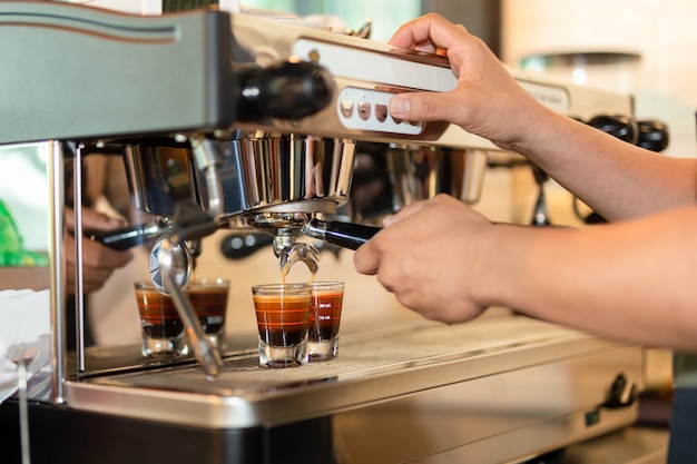 バリスタがコーヒー醸造用コーヒーからエスプレッソショットを準備します。