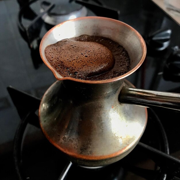 Photo barista preparing hot tasty drink from copper turk