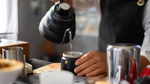 Foto barista's bereiden hete koffiebonen in een beker om koffie te zetten voor stoom koffiewinkelconcept in caféwinkel voor kleine bedrijven