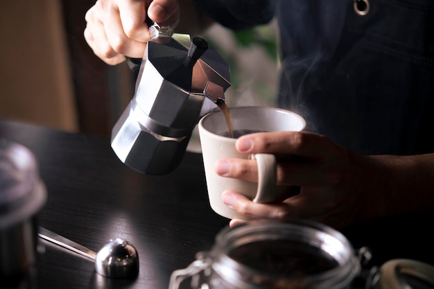 Barista schenkt koffie uit een mokapot-koffiezetapparaat naar een koffiekopje Hand met Italiaanse klassieke mokapot die koffie schenkt