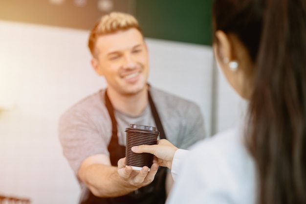 Barista serveert de koffie aan het loket aan de klant met een servicegerichte geest blij en glimlach?