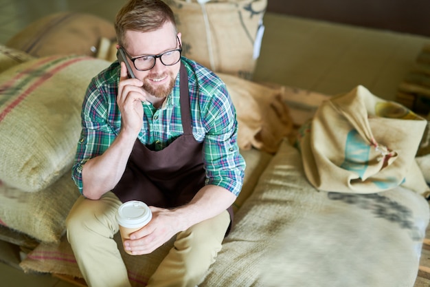 Barista seduto su borse con caffè