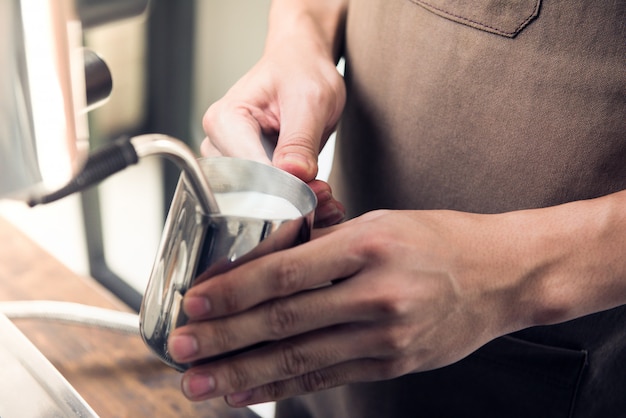 コーヒーメーカーで牛乳を蒸しているバリスタ