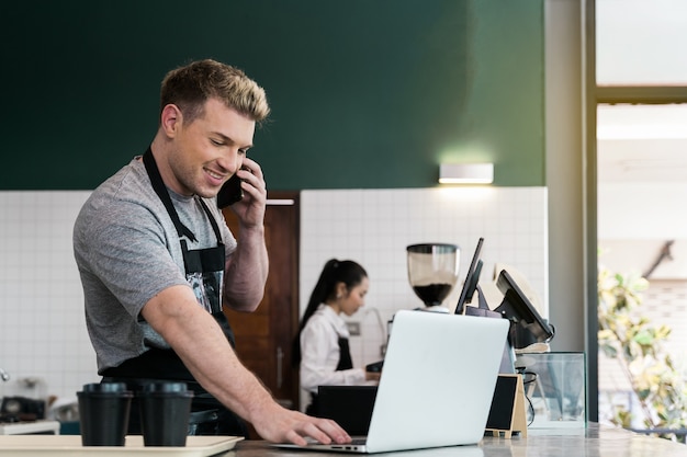 Foto barista usa il laptop per prendere l'ordine dal cliente nel caffè del bancone