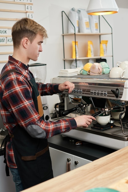 Barista using a coffee machine to make coffee in cafe