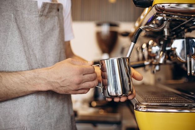 Barista warmt melk op bij een koffiezetapparaat