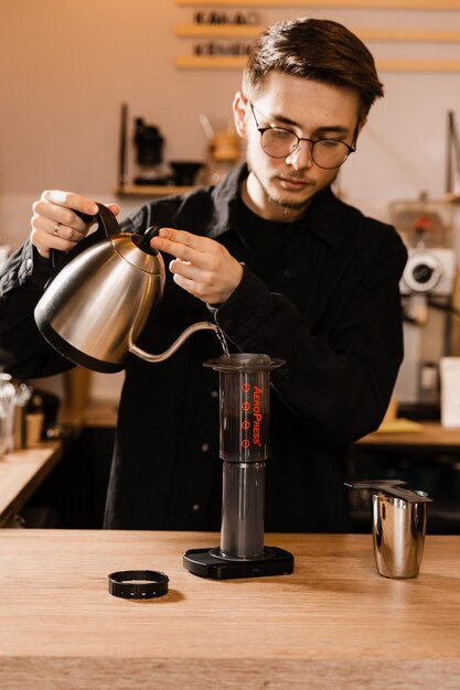 Barista zet aeropress koffie in café Proces van aeropress alternatieve methode koffie zetten Heet water gieten over gebrande en gemalen koffiebonen in aeropress