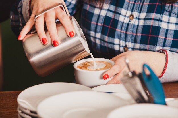 Foto barista zet een kopje latte art koffie, schenkt melk in met schuim