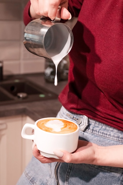 Baristameisje die latte kunstkoffie maken.