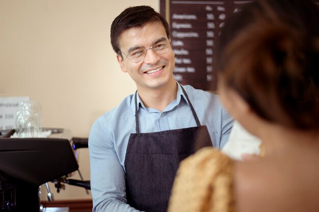 バリスタは、コーヒーショップで顧客に提供するためにホットコーヒーとパン屋のカップを手に取っています