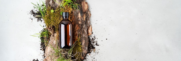 Photo bark tree, tiny mosses and grass of organic cosmetic products in glass brown bottle