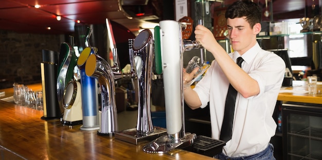 Barkeeper die glas voor bierautomaat houdt