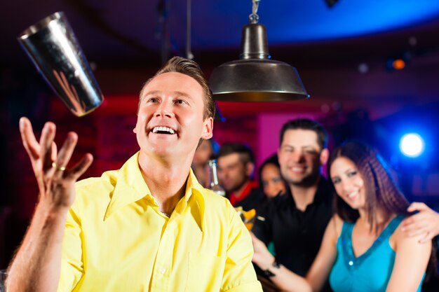 Photo barkeeper in a pub is mixing cocktails or drinks