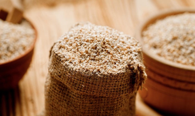 木製の背景にボウルやバッグに大麦の割り高品質の写真