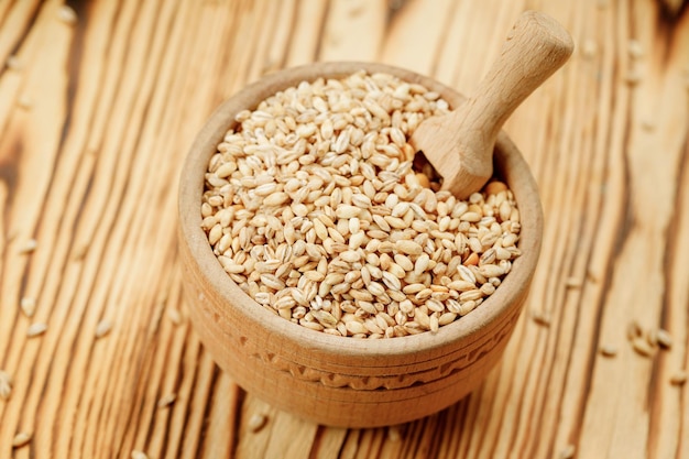 Barley groats in bowls and bags on a wooden background High quality photo