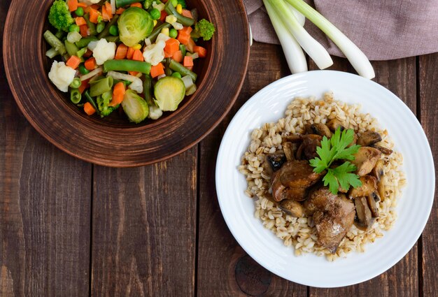 Barley porridge, fried mushrooms, duck liver and steamed summer vegetables. Top view