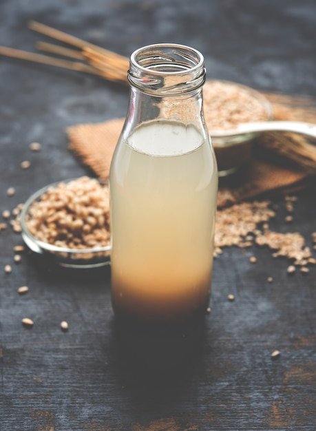 Photo barley water in glass with raw and cooked pearl barley wheat or seeds. selective focus