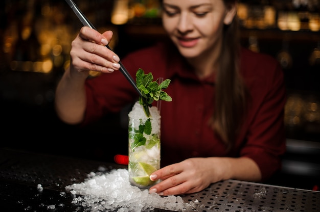 Barmaid completes the design of the mojito alcohol cocktail