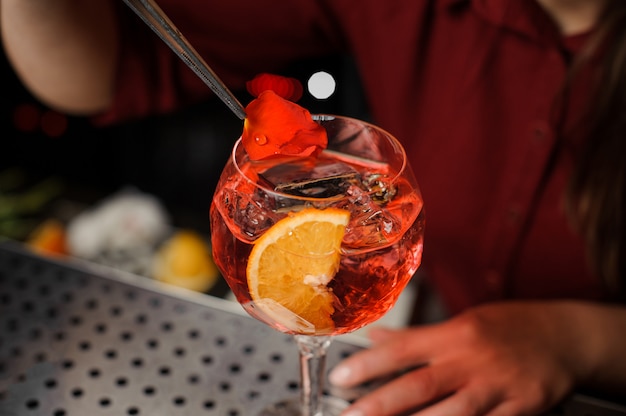 Barmaid finishes the preparation of Spritz Veneziano, adding a rose petal