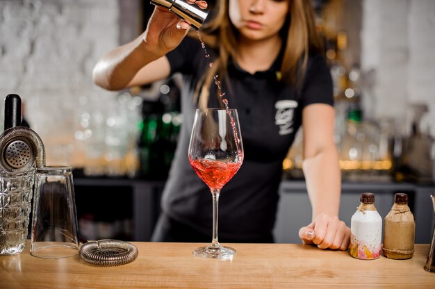 Barmaid mixing cocktails at the bar counter using bar equipment