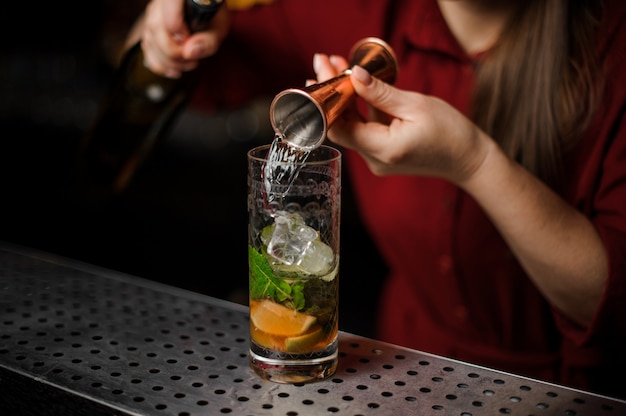 Barmaid prepares a mojito, adding white rum