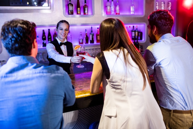 Barmaid serving drink to woman