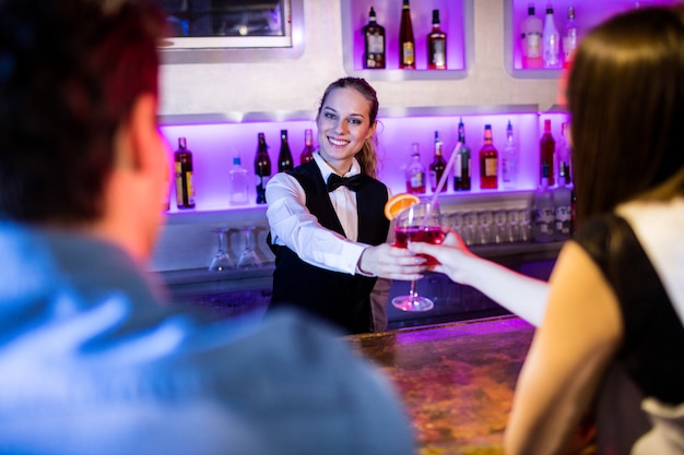 Barmaid serving drink to woman