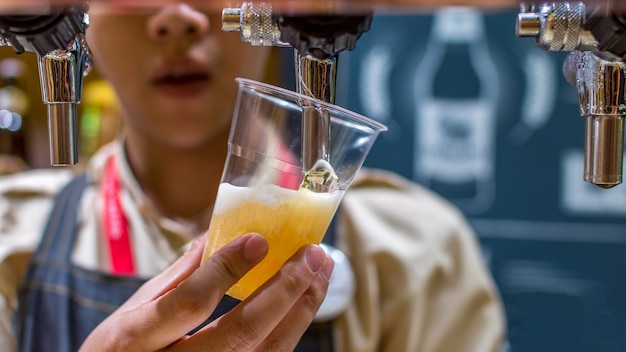 Photo barman or bartender pouring a draught lager beer from beer tap on counter