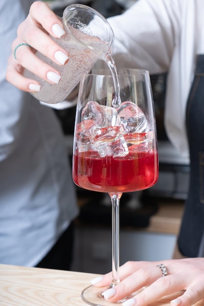 Barman bereidt alcoholische cocktails met ijs in glazen op de bartafel