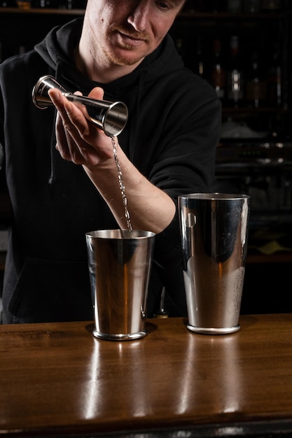 Barman bereidt klassieke Clover club alcoholische cocktail aan de bar Barman mengt eiwit, citroen, droge vermout en gin om de Clover club cocktail te bereiden