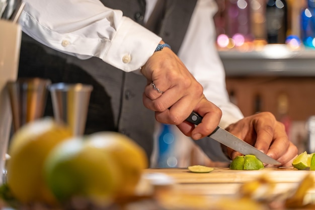 Barman cutting lime on bar counter