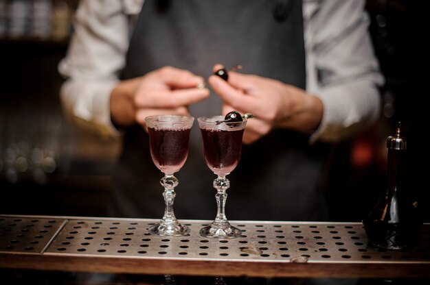 Barman decoreert twee glazen gevuld met sterke Arnaud-zomercocktail