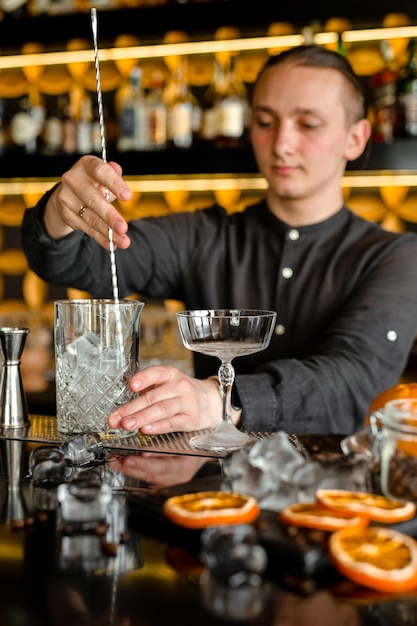 Barman die een alcoholische verse rode luxecocktail uitvoert aan de bar Versierd met sinaasappels
