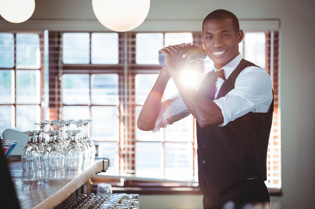 Barman die een cocktaildrank in cocktailshaker mengen