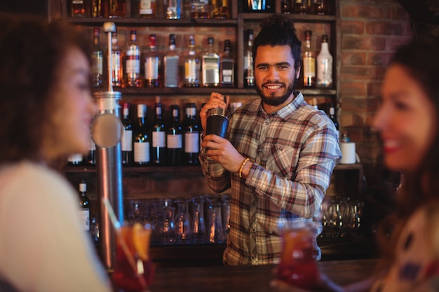 Barman die een cocktaildrank in cocktailshaker mengt