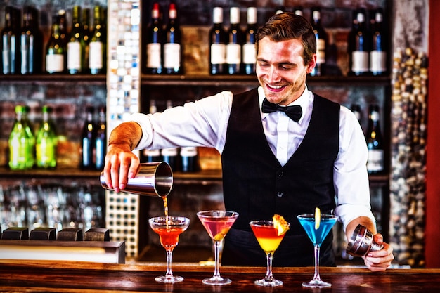 Barman die een oranje martini-drank in het glas giet