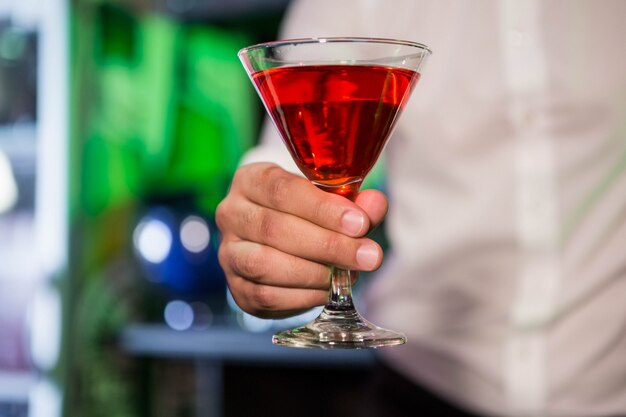 Barman die een rode martini in bar dienen